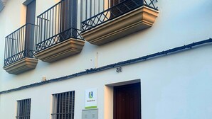A building with a white facade, multiple windows with metal bars, and a door with a dark-colored door frame. - Vrbo Property (Encinasola)