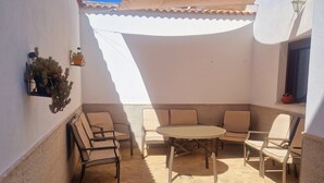 A patio with a round table and four chairs, a sofa, and two potted plants. - Vrbo Property (Encinasola)