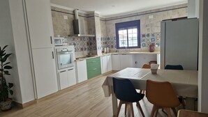 A kitchen with a dining area, featuring a tiled backsplash, a window, and a microwave. - Vrbo Property (Encinasola)
