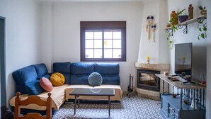 A living room with a blue sofa, a small table, a fireplace, and a television. - Vrbo Property (Encinasola)