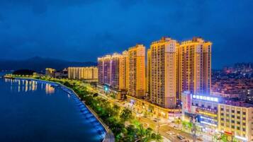 Un hotel frente al agua con varios edificios altos, un paseo marítimo y vista al paisaje urbano.