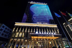 A hotel with a prominent illuminated facade and a clear sign indicating its name. - Clear Lake Hotel (Shanwei)