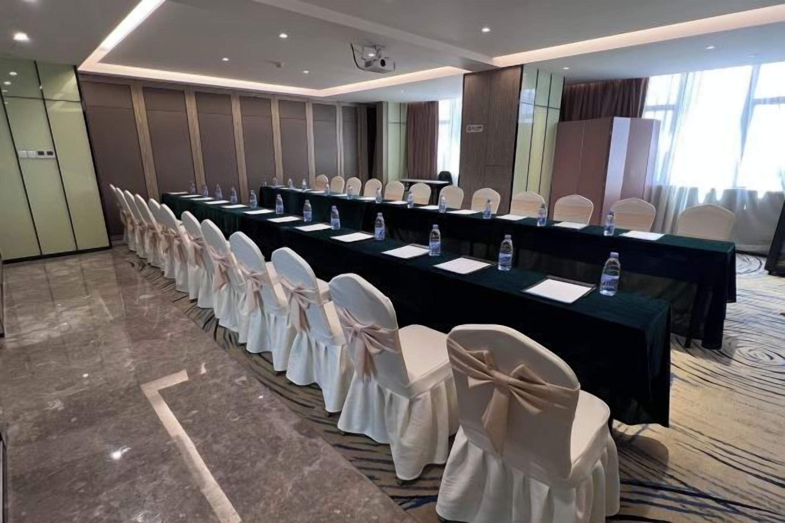A conference room with a long table, chairs, and a projector screen.