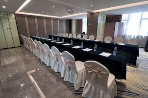 Un salón de conferencias con una larga mesa, sillas y una pantalla para proyector.