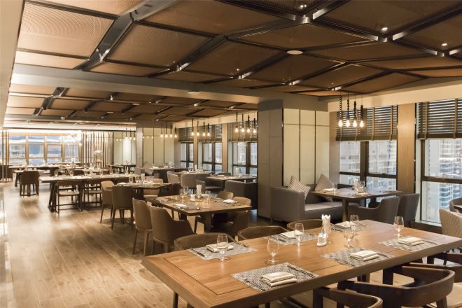 A spacious restaurant with high ceilings, multiple dining tables, and large windows allowing natural light.