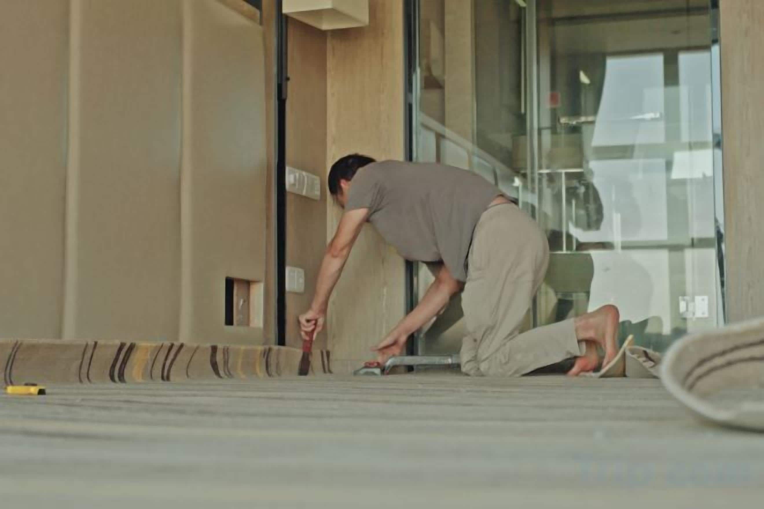 A person lying on the floor near a building entrance, possibly in a state of rest or recovery.