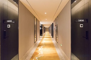 Un pasillo de hotel con puertas identificadas con los números 1905 y 1902, piso de aspecto marmolizado y diseño moderno.