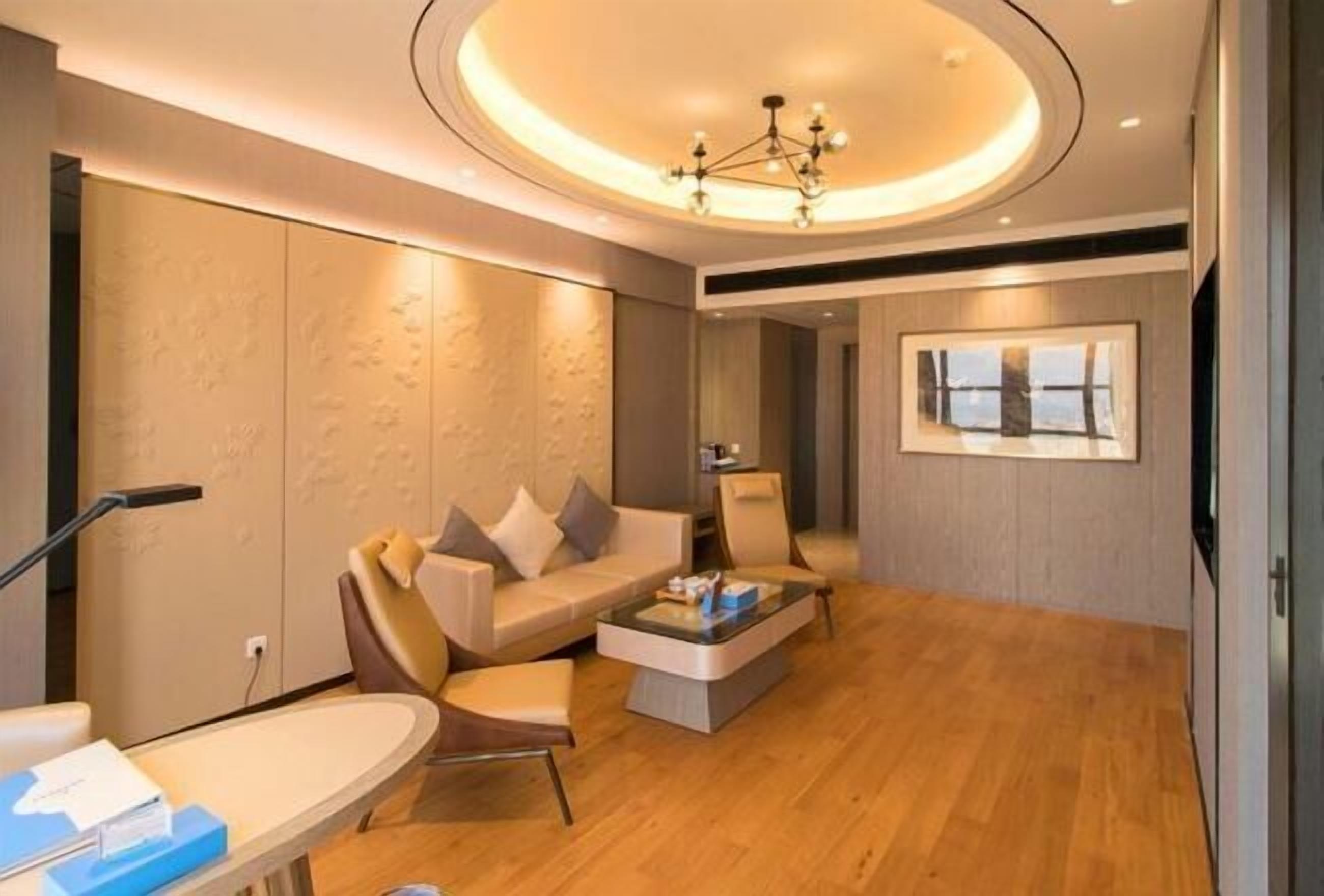 A modern living room with a sofa, chairs, a coffee table, and a chandelier.