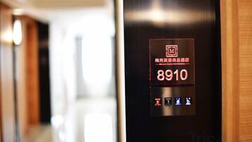 A hotel elevator control panel with a digital display indicating room number 8910.