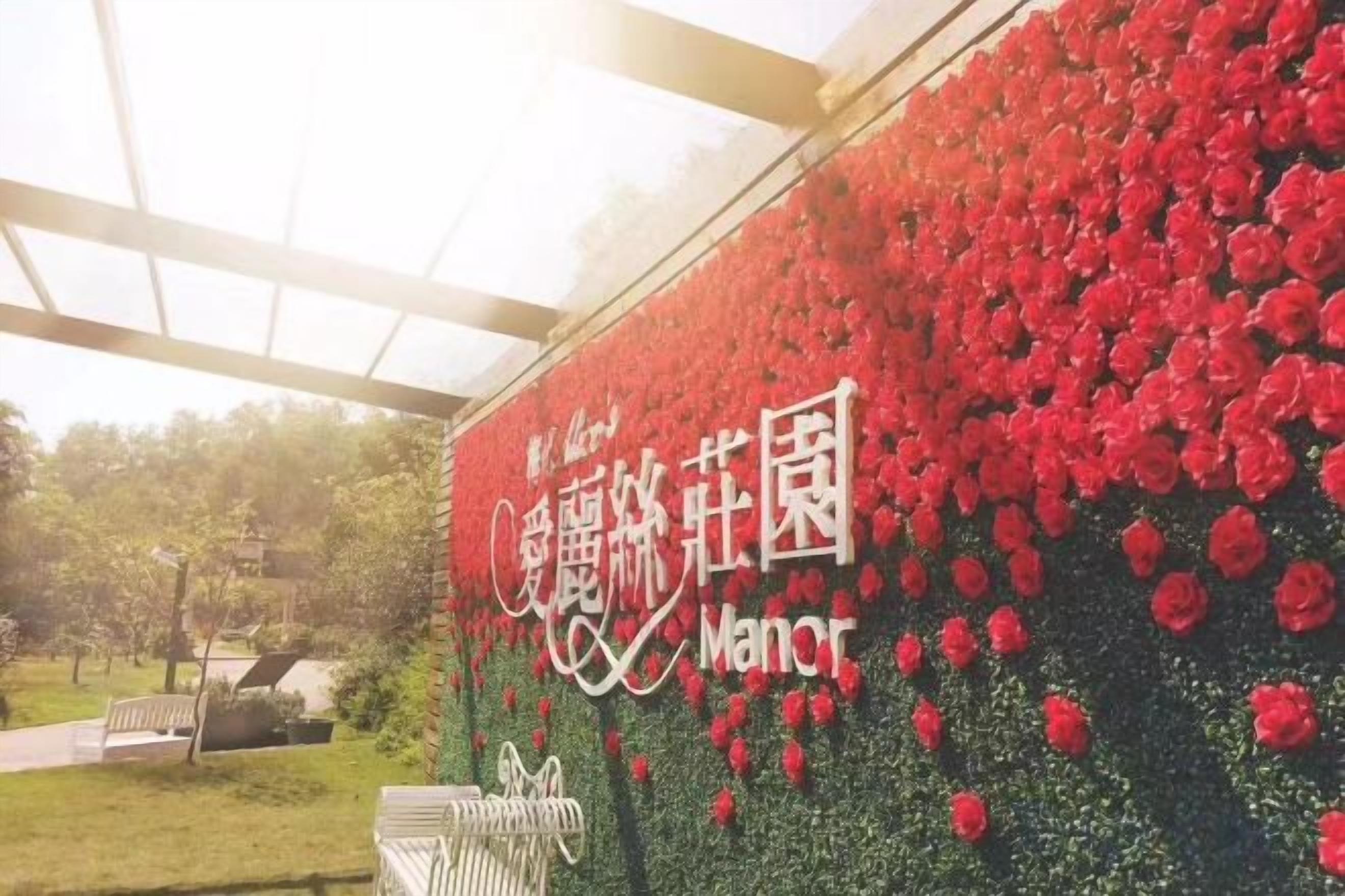 A wall covered with red flowers and a sign with Chinese characters.