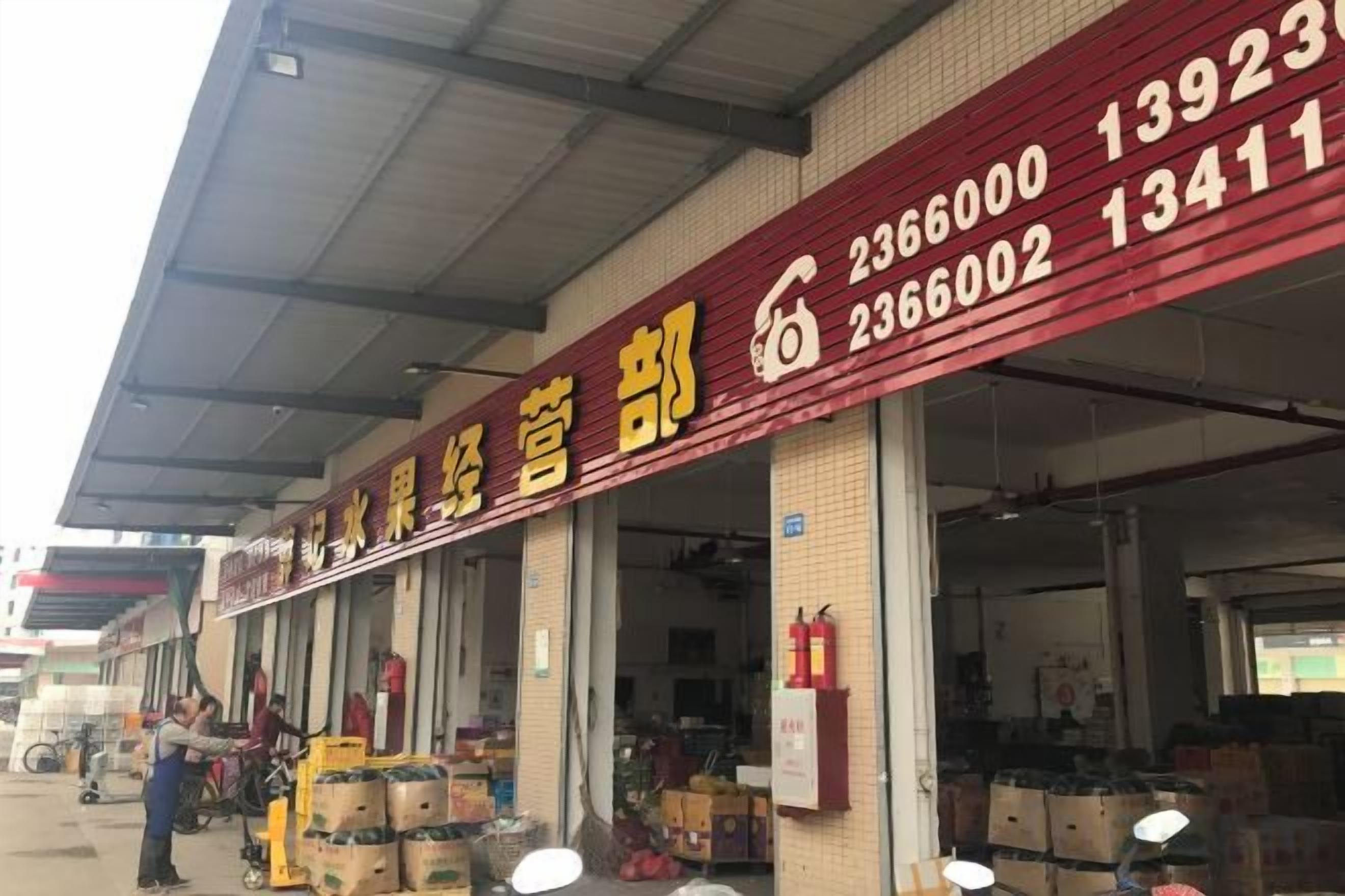 A warehouse with large doors and a red sign with contact numbers.