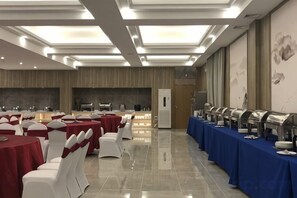 A banquet hall with round tables, white chairs, and a buffet line. - Mercure Styles Hotel Meizhou (Meizhou)