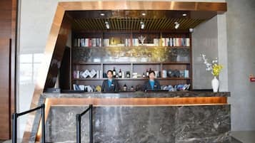 A reception desk with a marble top, a wooden counter, and a bookshelf filled with books and decorative items.