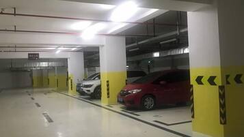 A parking garage with multiple parking spaces, yellow and white pillars, and a red car parked in one of the spaces.