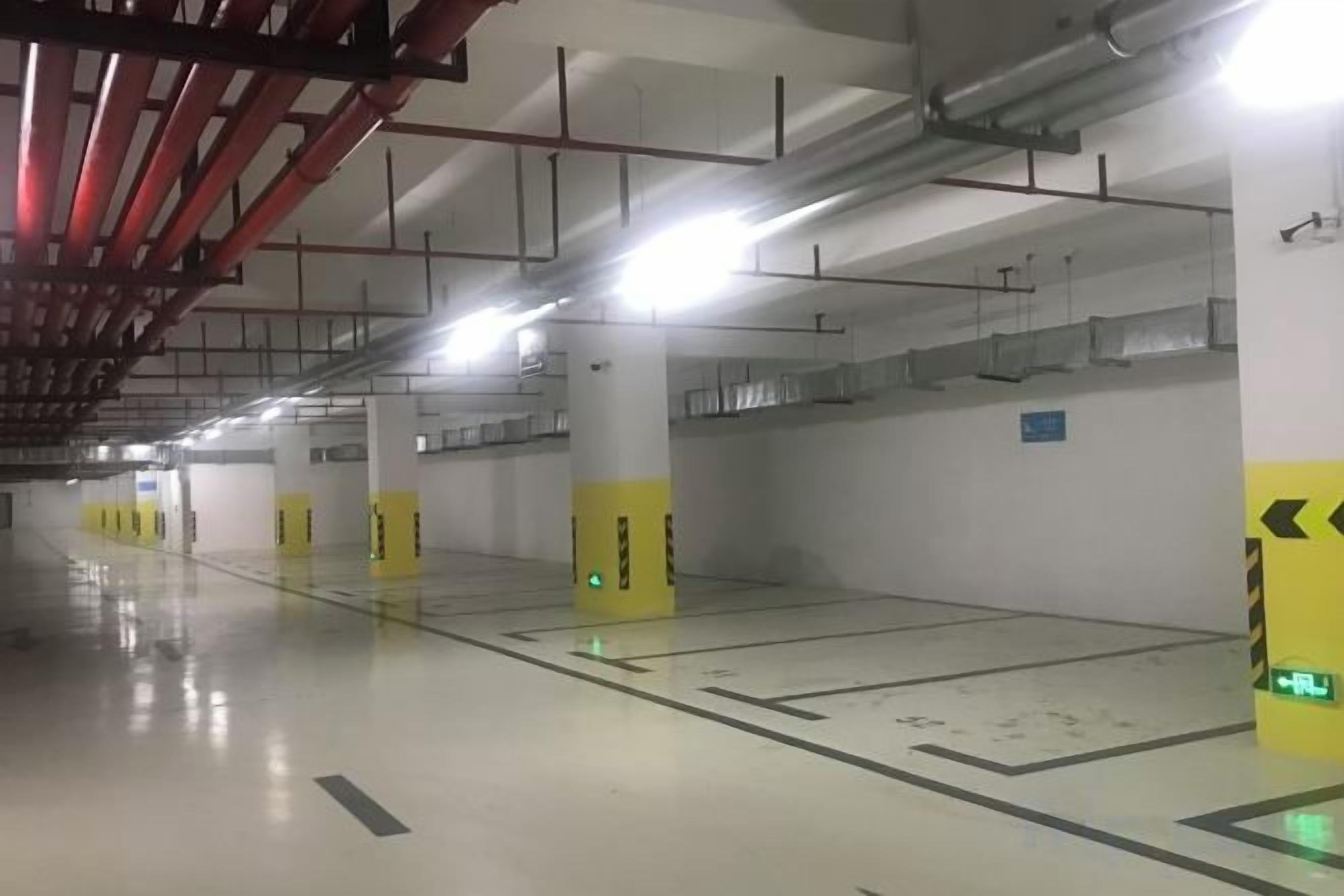 Un parking vide aux murs blancs, aux piliers jaunes et aux flèches directionnelles peintes sur le sol.