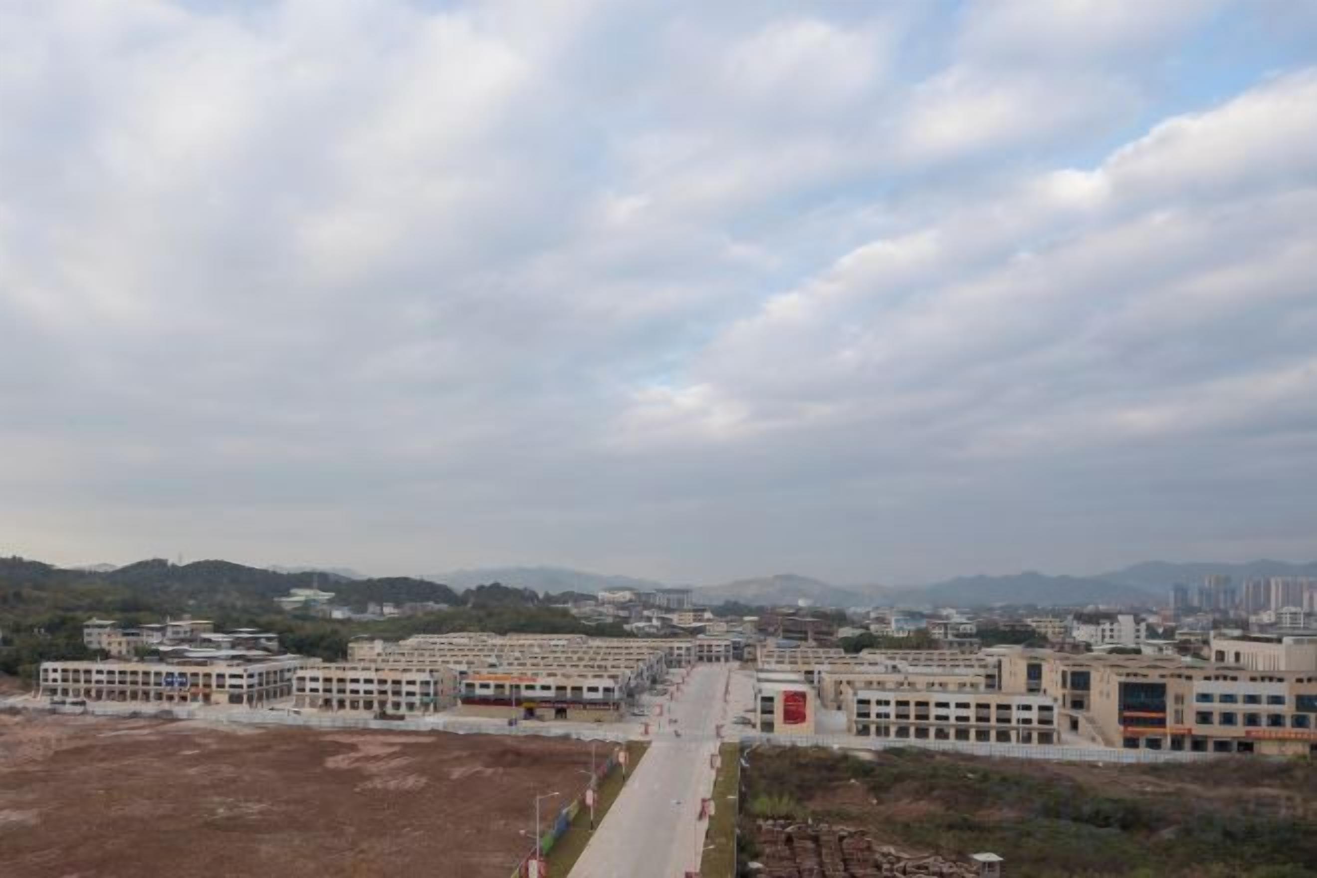 A large building complex with multiple structures, a central open area, and a distant mountain range.