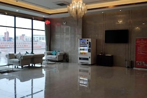 A hotel lobby with a seating area, a vending machine, and a large window offering a view of the city. - Mercure Styles Hotel Meizhou (Meizhou)