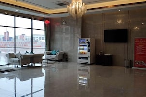 Un vestíbulo de hotel con un área de descanso, una máquina expendedora y un amplio ventanal con vistas a la ciudad.