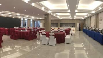 A banquet hall with round tables, white chairs, and a long table with blue tablecloths.
