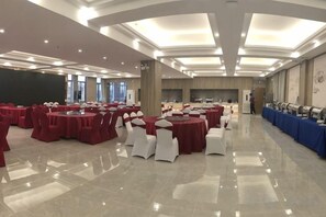 A banquet hall with round tables, white chairs, and a long table with blue tablecloths. - Mercure Styles Hotel Meizhou (Meizhou)
