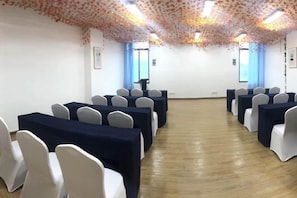 A conference room with rows of tables and chairs, a projector screen, and a wooden floor. - Mercure Styles Hotel Meizhou (Meizhou)