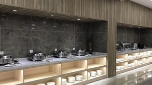 Disposição moderna de buffet com diversas estações de serviço, uma parede de mármore e um pilar de madeira.