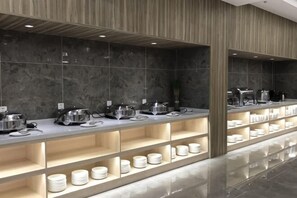 A modern buffet setup with multiple serving stations, a marble wall, and a wooden column. - Mercure Styles Hotel Meizhou (Meizhou)