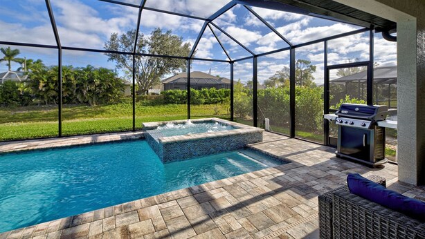 A covered outdoor swimming pool with a hot tub, a grill, and a wicker sofa. - Blue Pearl| Pool | Hot Tub | 3 Bed, 2 Bath (Rotonda West)