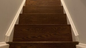 Un escalier en bois avec des rampes blanches et un plancher en bois foncé.