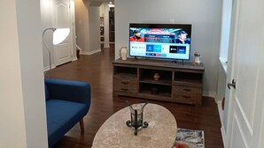 Un salon moderne avec un téléviseur à écran plat fixé au mur, un canapé bleu, une table basse et un meuble en bois placé sous le téléviseur.