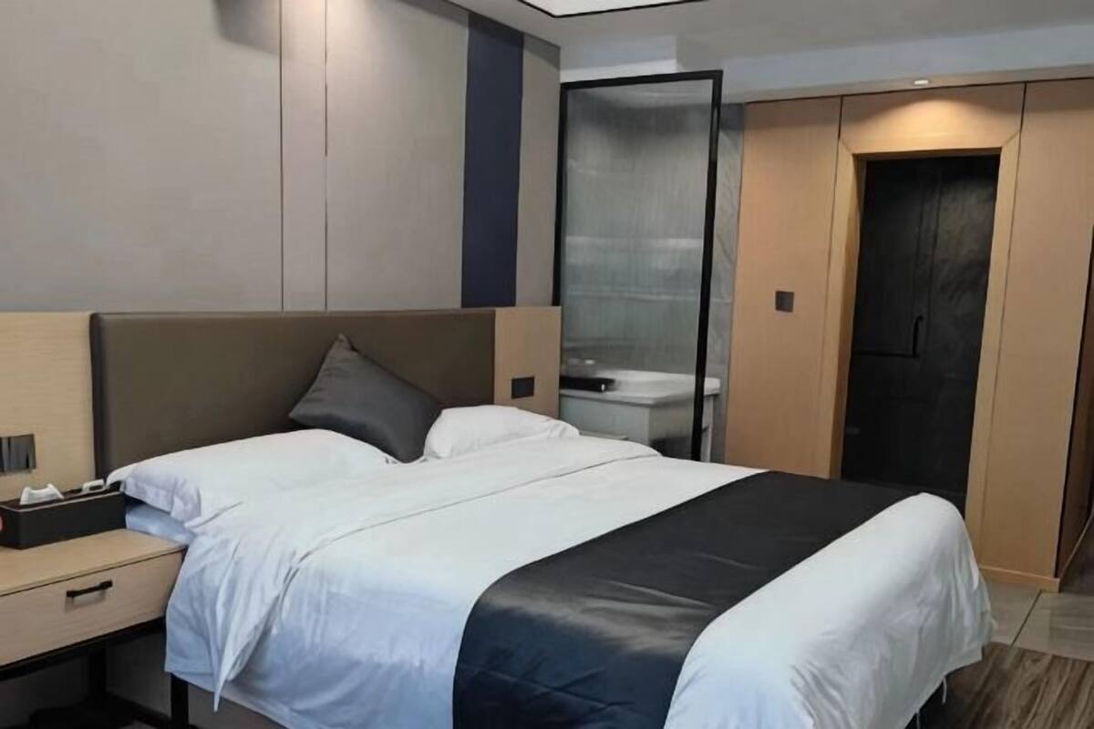 Une chambre d’hôtel moderne, équipée d’un lit, d’une table de chevet et d’une armoire.