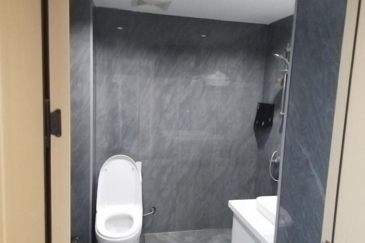 A bathroom with a toilet, a shower, and a sink.