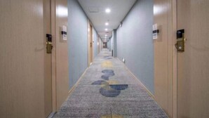 Un largo y estrecho pasillo de hotel con pisos alfombrados y puertas de madera a ambos lados.