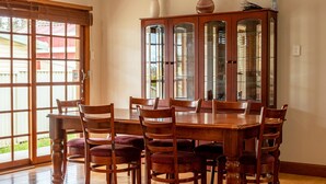 A dining area with a wooden table and chairs, a glass-fronted cabinet, and a sliding glass door leading to a patio.