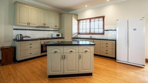 A kitchen with light-colored cabinets, a central island, a refrigerator, and a microwave.