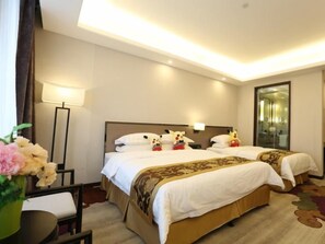 Une chambre d’hôtel avec deux lits, une table de chevet, une lampe et un miroir.