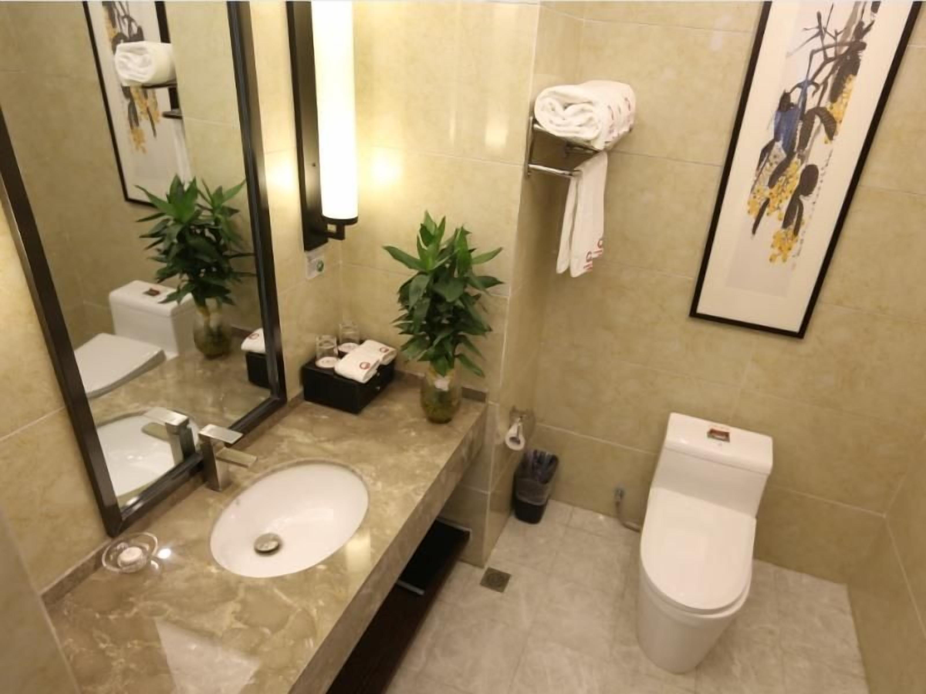 A bathroom with a sink, mirror, toilet, and a towel rack.