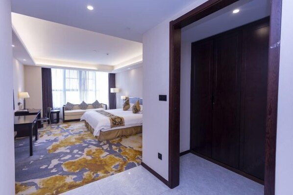 Une chambre d’hôtel avec un lit, un bureau, une chaise et une grande fenêtre.
