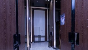 Käytävä, jonka seinät ovat puuta, lattia on laatoitettu ja käytävän päässä on ovi.