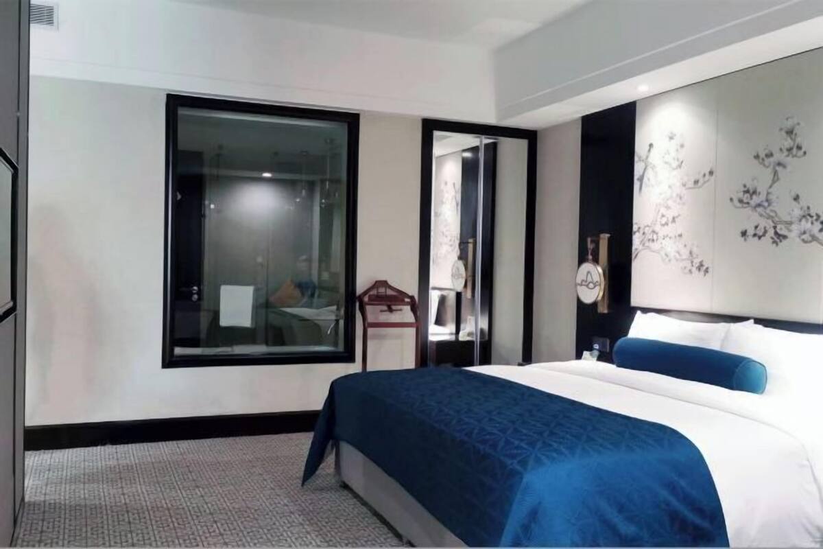Une chambre d’hôtel avec un grand lit, un mur en verre et un élément décoratif mural.