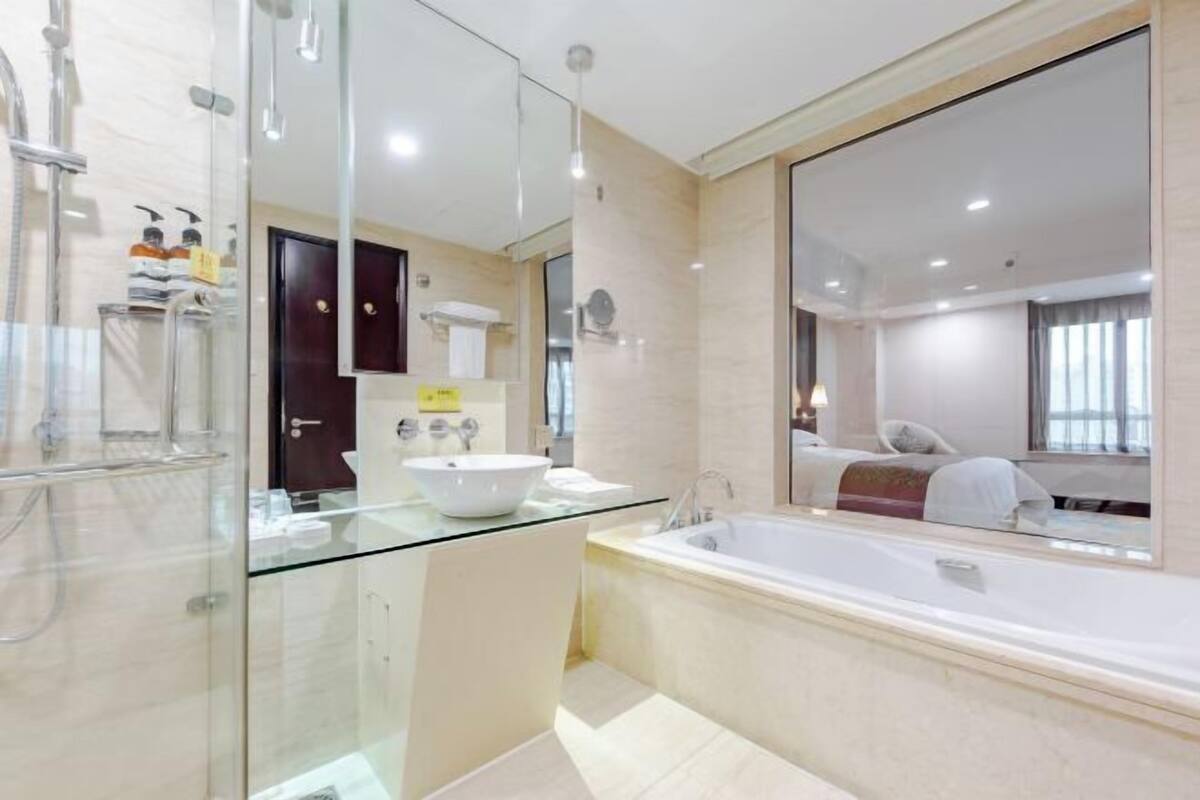 A modern bathroom with a glass shower enclosure, a freestanding bathtub, and a large mirror.