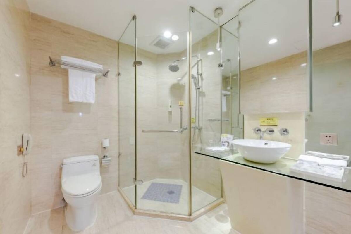 A modern bathroom with a glass-enclosed shower, a white toilet, and a glass-topped vanity with a white sink.