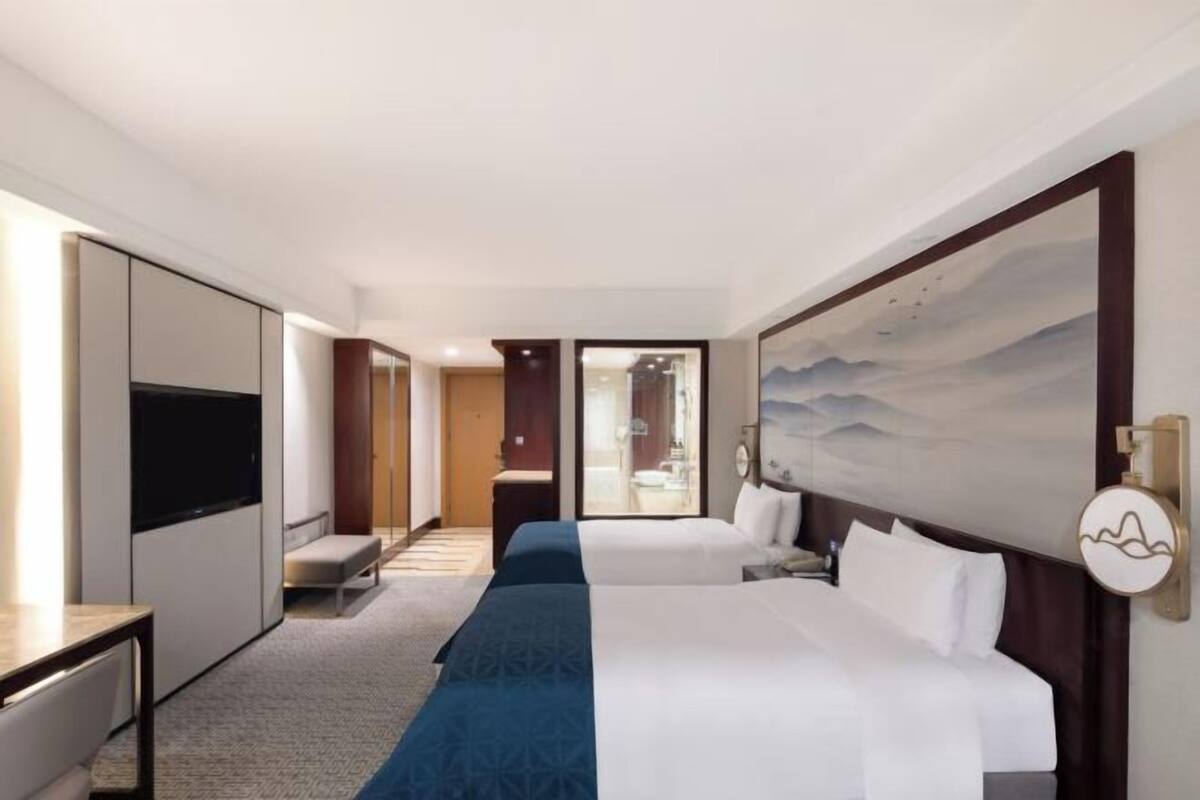 Une chambre d’hôtel avec un grand lit, une télévision, un bureau et un tableau au mur.
