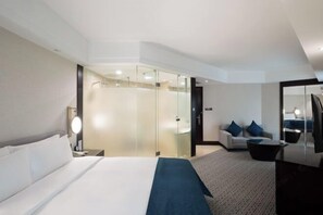A modern hotel room with a large bed, a sofa, a desk, and a glass partition. - Tianze Enjoy Hotel (Fuqing)