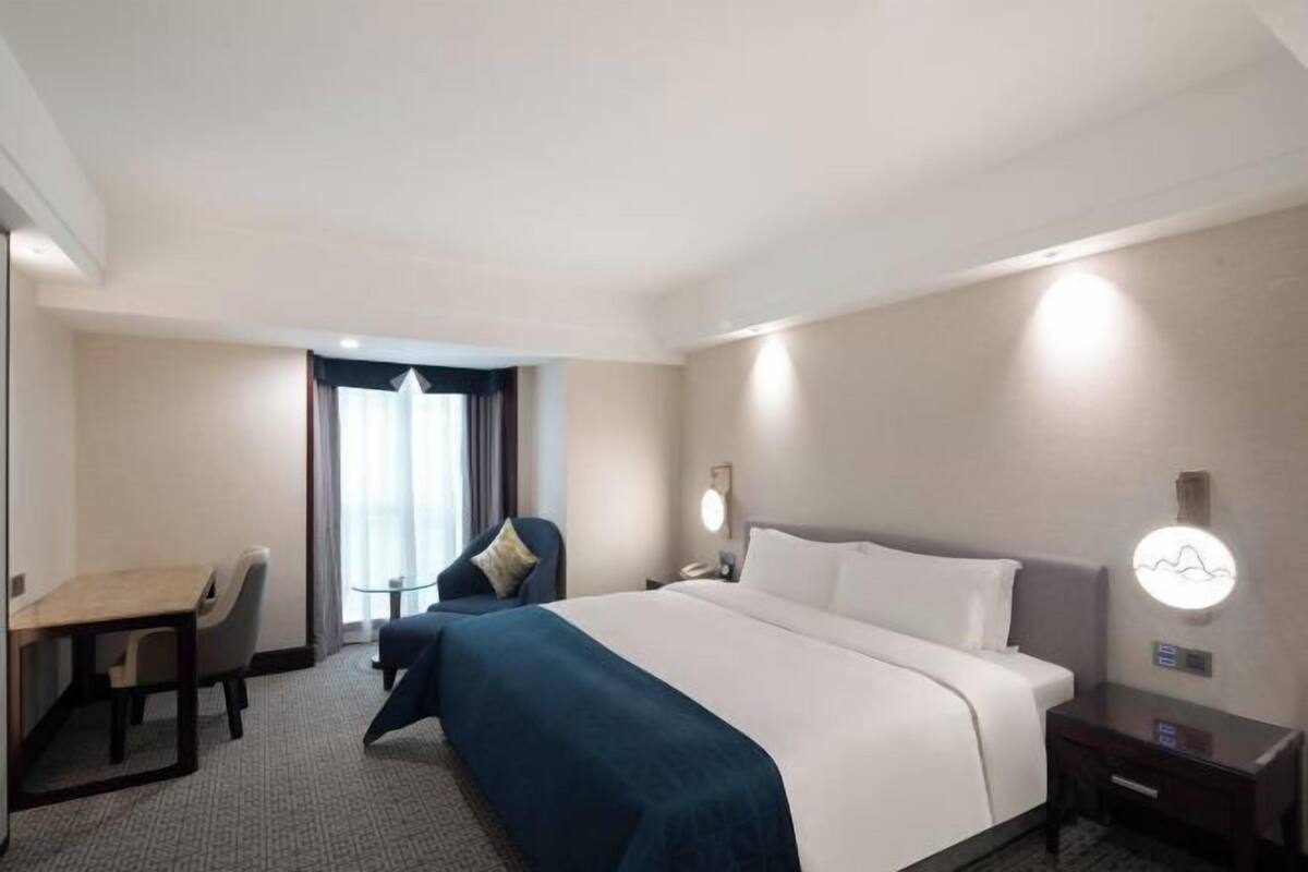 Une chambre d’hôtel avec un lit, un bureau, une chaise et une table de chevet.