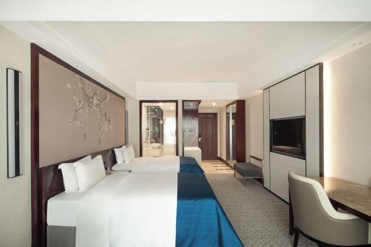 A hotel room with a large bed, a desk, a chair, and a TV.