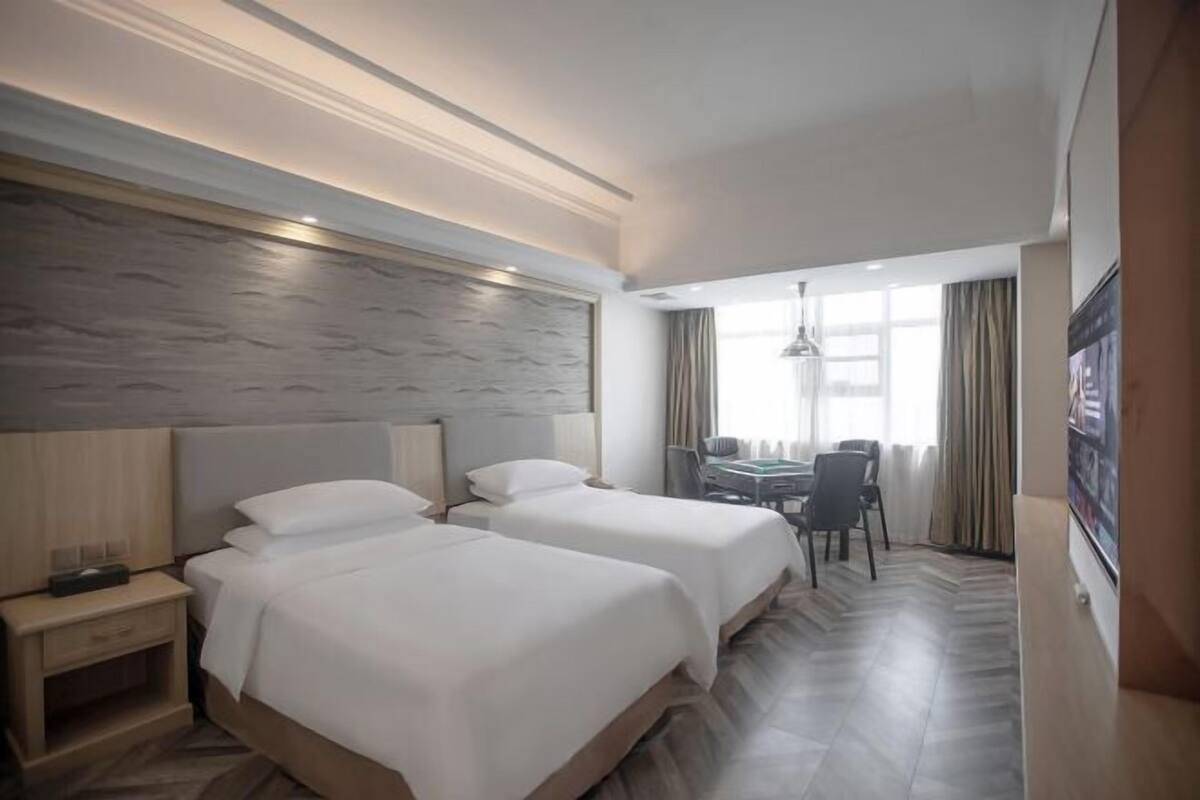 A hotel room with two beds, a desk, and a chair.