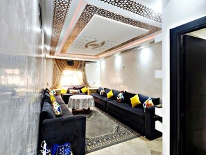 Un salon comprenant un ensemble de canapés, un tapis à motifs et un plafond décoratif.