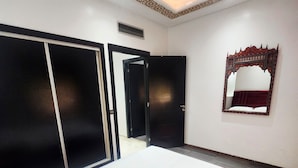 Une chambre dotée d’un grand lit, d’une armoire, d’un miroir et d’un plafond décoratif.