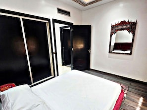 Een hotelkamer met een bed, een kledingkast, een spiegel en een deur.